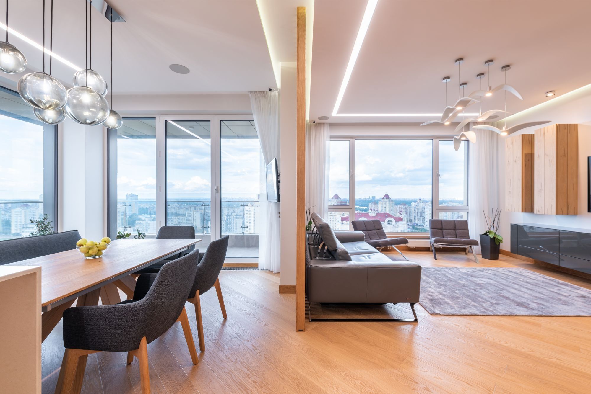 Salón comedor luminoso con ventanales y vistas a la ciudad